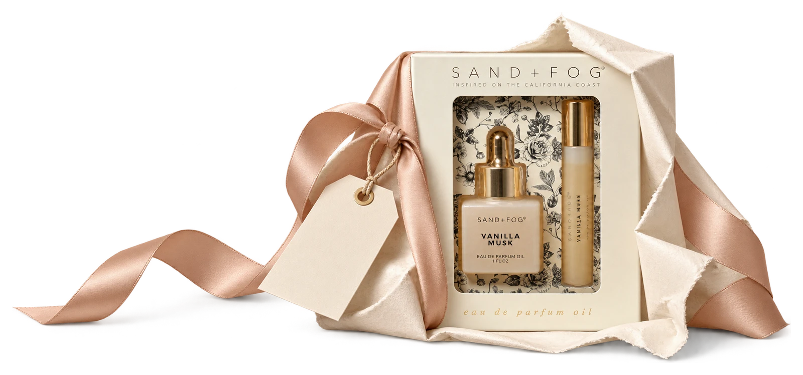 The actual Vanilla Musk perfume-oil gift set partly wrapped with an untied blush ribbon and blank gift tag.