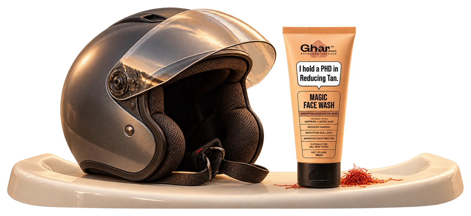 The actual peach Ghar Soaps face-wash tube on a sink rim near a helmet and a few saffron threads.