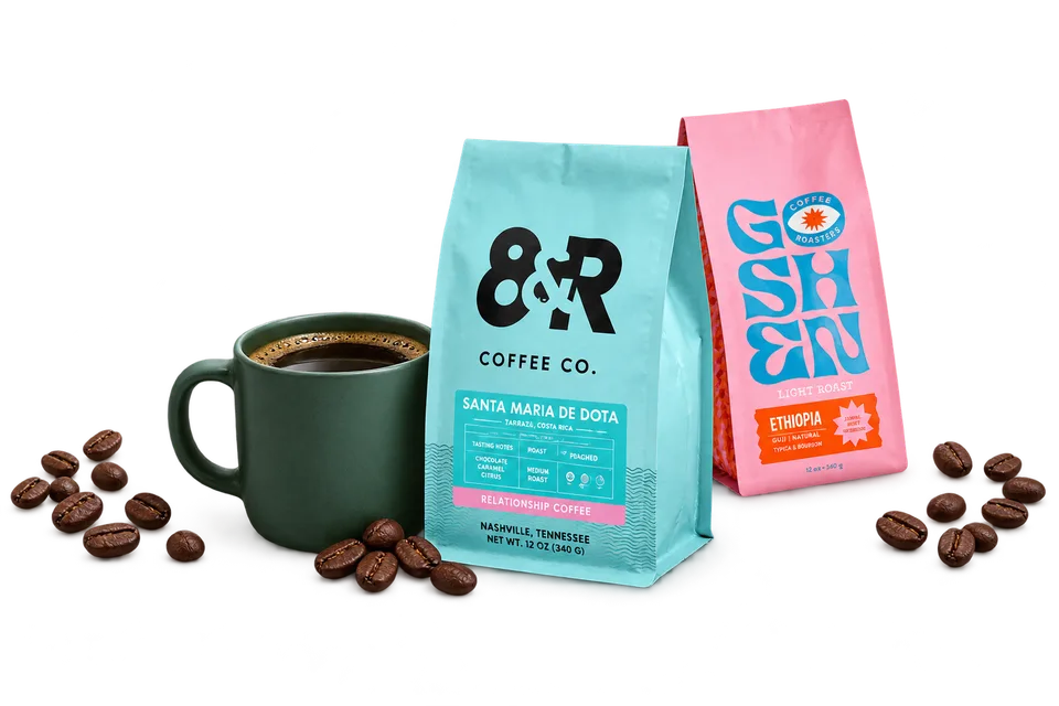 A coffee selection with turquoise and pink independent roaster bags and a green coffee cup.
